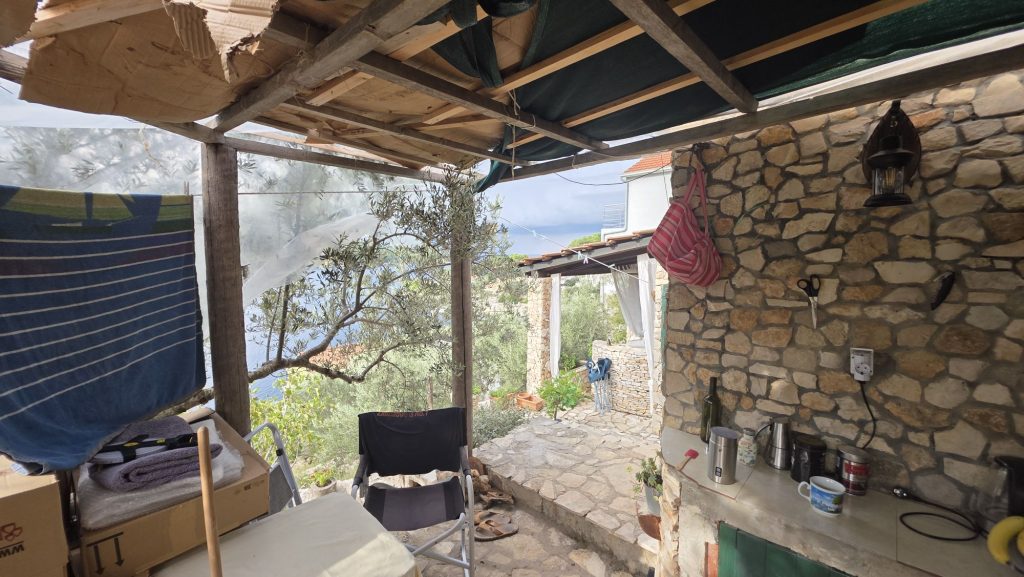 Seitenblick auf die Terrasse mit Olivenbaum und provisorischem Dach