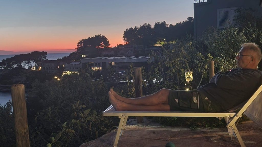 Mann liegt entspannt auf einer Liege mit Blick auf den Sonnenuntergang