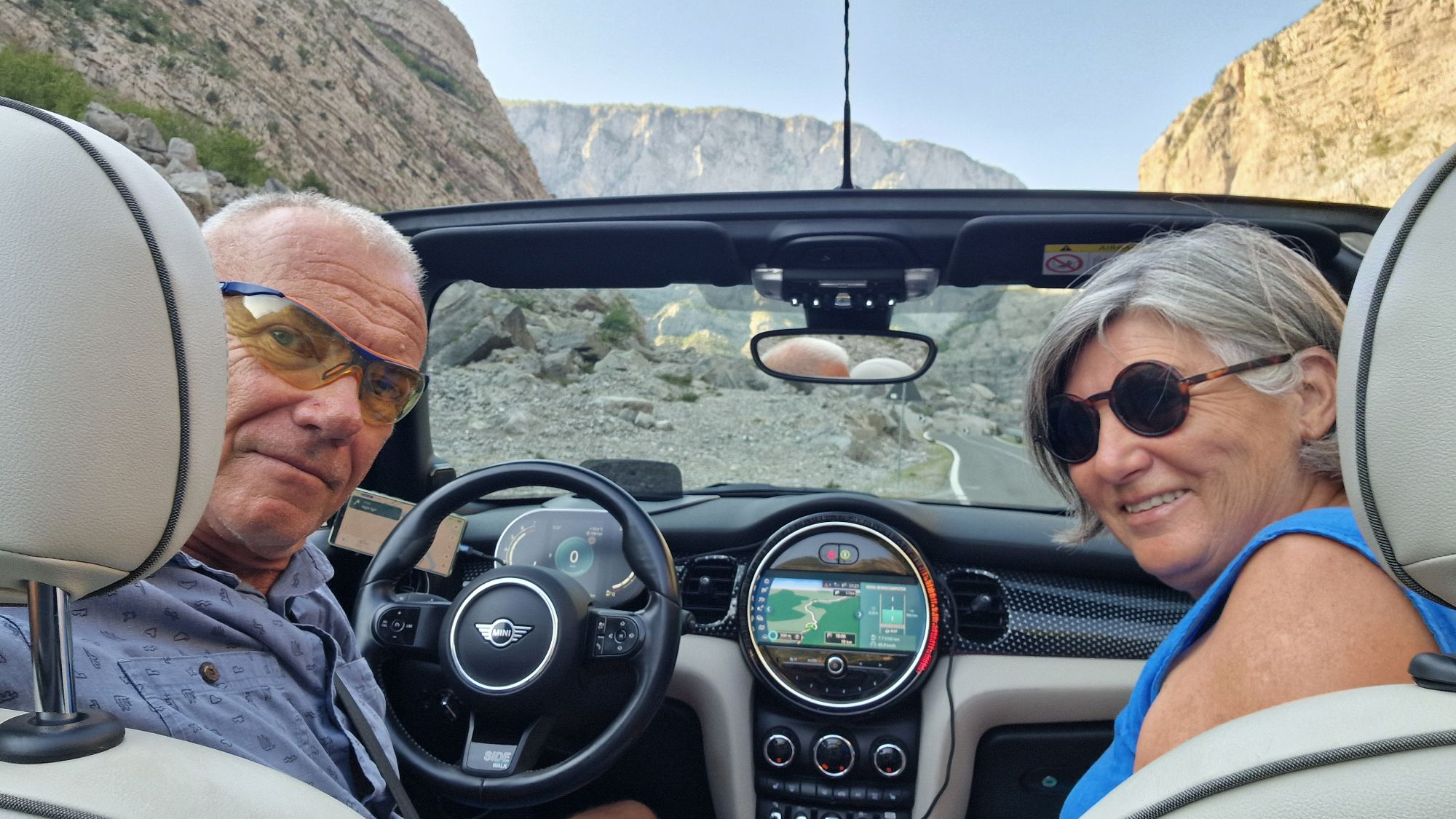 Fahrt mit geöffnetem Cabriodach durch ein schattiges Bergtal